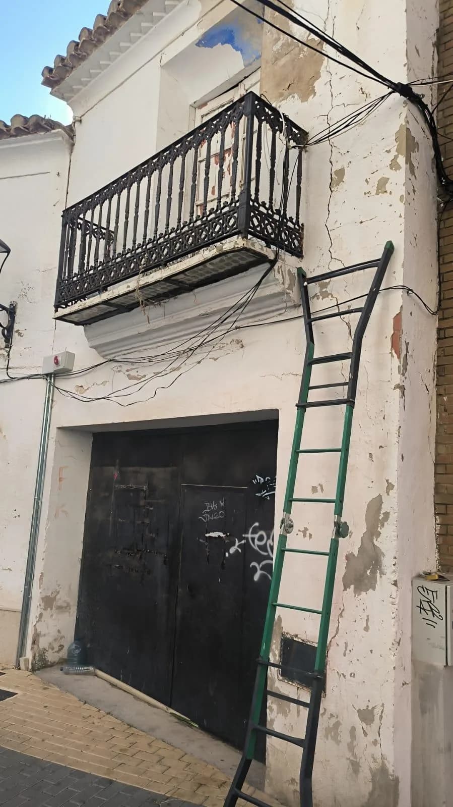 Escalera apoyada en la fachada de la casa abandonada, bajo el balcón del rescate